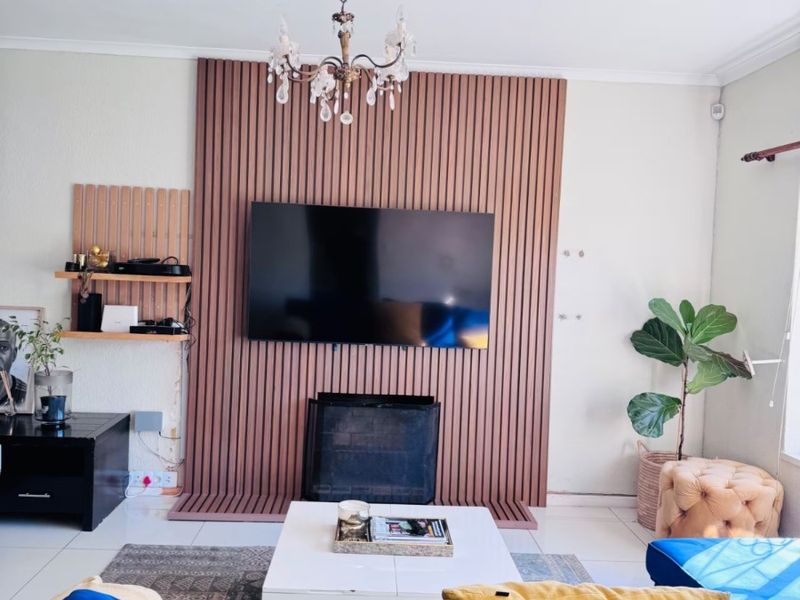 Living room featuring a modern slatted wood accent wall with a built-in fireplace and tiled flooring.