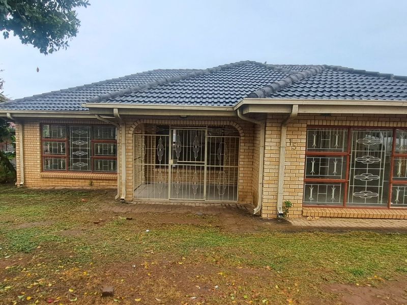 Front elevation of a single-story face brick house featuring a tiled roof, security gates, and metal window frames with a front garden area.