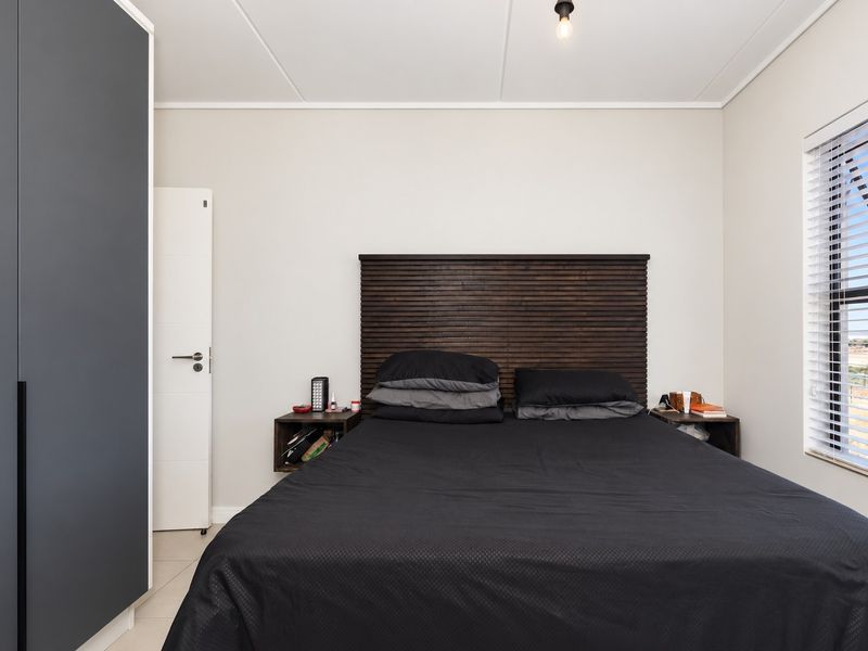 A well-maintained bedroom featuring a built-in wardrobe, a decorative slatted timber headboard, and venetian blinds allowing natural light.