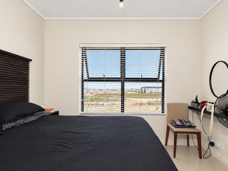 A well-maintained bedroom featuring a large casement window with venetian blinds, offering natural light and an expansive exterior view.
