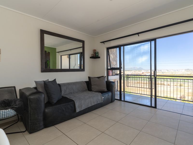 Bright living room featuring neutral tiled flooring and large sliding glass doors that open onto a balcony with scenic views.