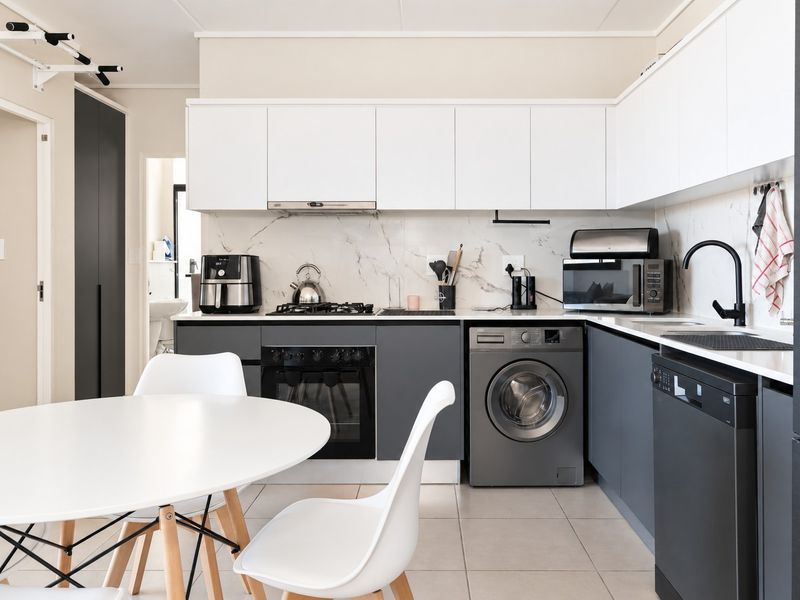 Modern kitchen featuring sleek two-tone cabinetry, marble-look backsplash, integrated appliances, and high-quality matte black fixtures, offering a clean and functional culinary space.