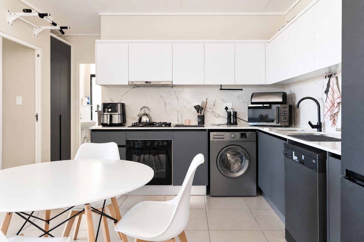 Modern kitchen featuring sleek two-tone cabinetry, marble-look backsplash, integrated appliances, and high-quality matte black fixtures, offering a clean and functional culinary space.