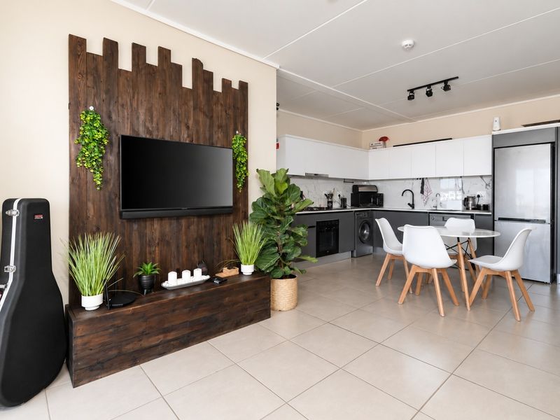 Modern open-plan living area featuring a contemporary kitchen with sleek cabinetry, integrated appliances, and a stylish timber feature wall in the lounge space.