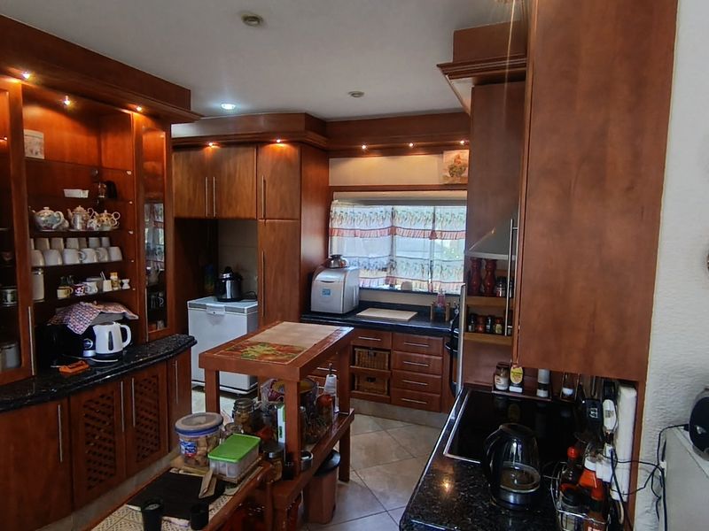 A traditional kitchen featuring extensive built-in wooden cabinetry, granite countertops, and integrated lighting, offering a warm and functional workspace.