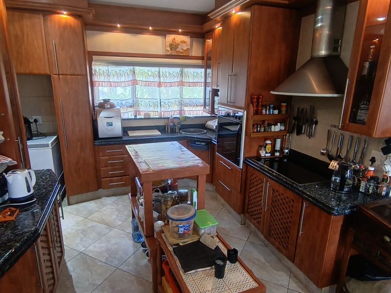 A traditional kitchen featuring extensive wooden cabinetry, granite countertops, built-in oven, and a central island, offering ample storage and workspace.
