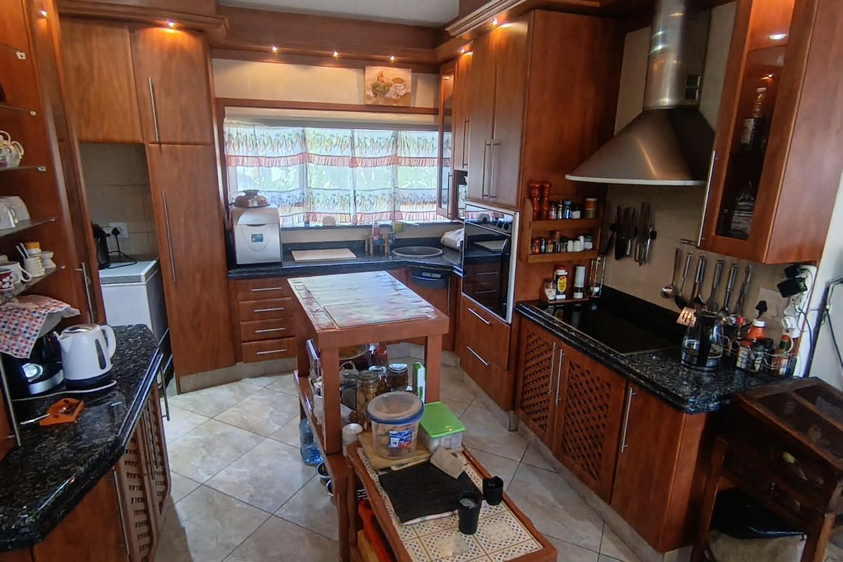 A traditional kitchen featuring extensive wooden cabinetry, granite countertops, built-in oven, and a central island, offering ample storage and workspace.