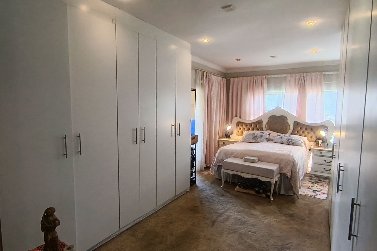 Spacious bedroom featuring extensive built-in cupboards, recessed downlighting, and carpeted flooring, offering a functional and well-organized living space.