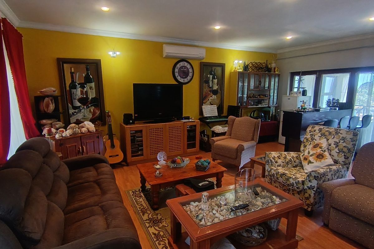 Spacious living room featuring laminate flooring, recessed downlighting, and a wall-mounted split-system air conditioner, with direct access to an outdoor area.