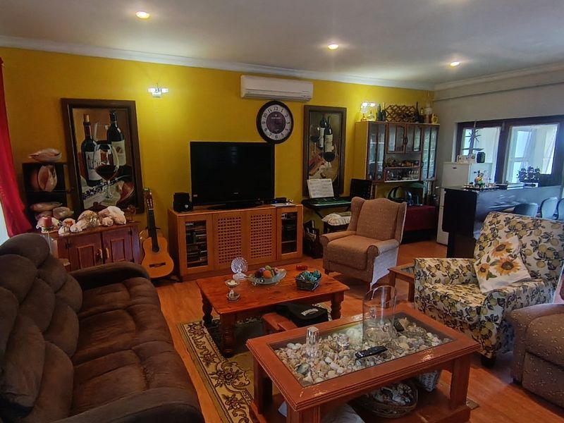 Spacious living room featuring laminate flooring, recessed downlighting, and a wall-mounted split-system air conditioner, with direct access to an outdoor area.