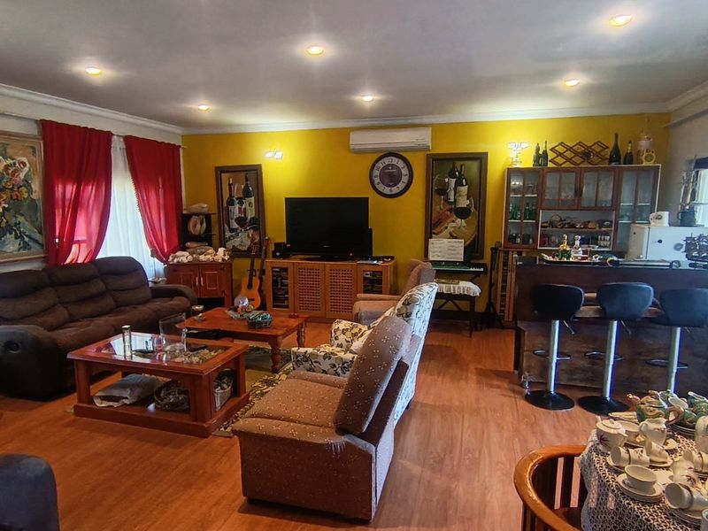 Spacious open-plan living area featuring laminate flooring, recessed lighting, a split-system air conditioner, and a built-in bar area.
