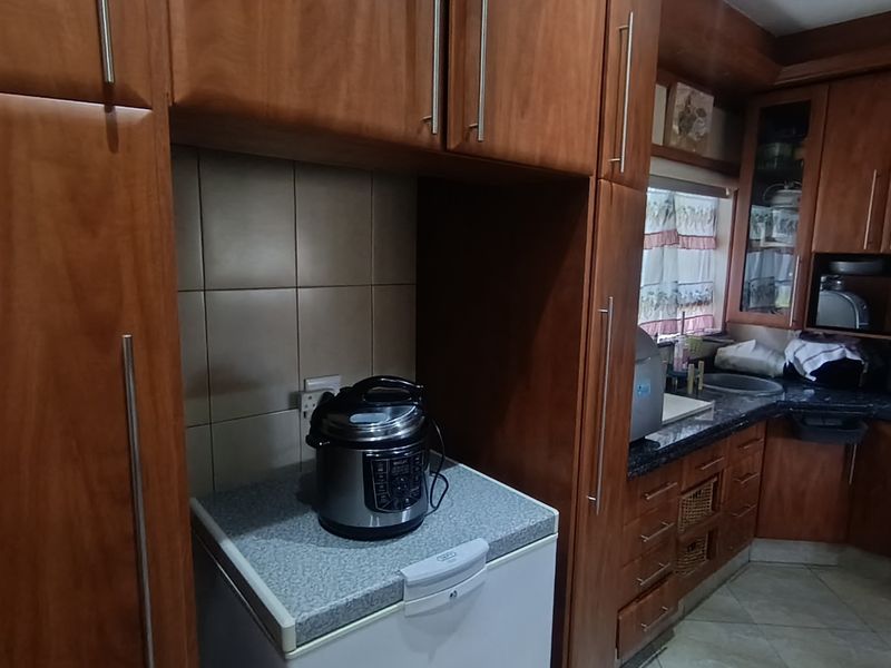 A functional kitchen featuring wood-finish cabinetry, tiled backsplash, and integrated oven, offering ample storage and workspace for daily meal preparation.