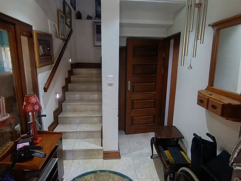 Entrance foyer featuring a tiled staircase with a wooden handrail, solid wood door, and neutral ceramic floor tiling.