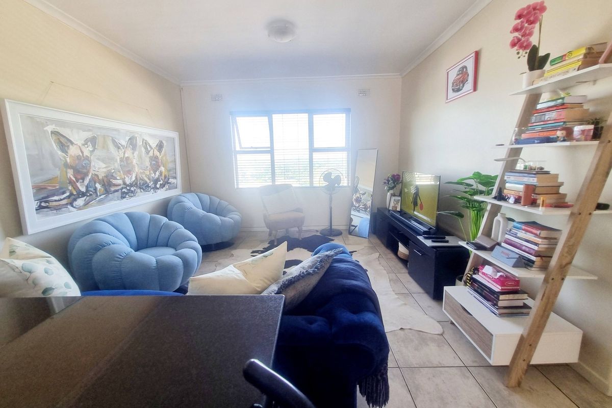 A living room featuring tiled flooring and a large window, providing natural light to the space.