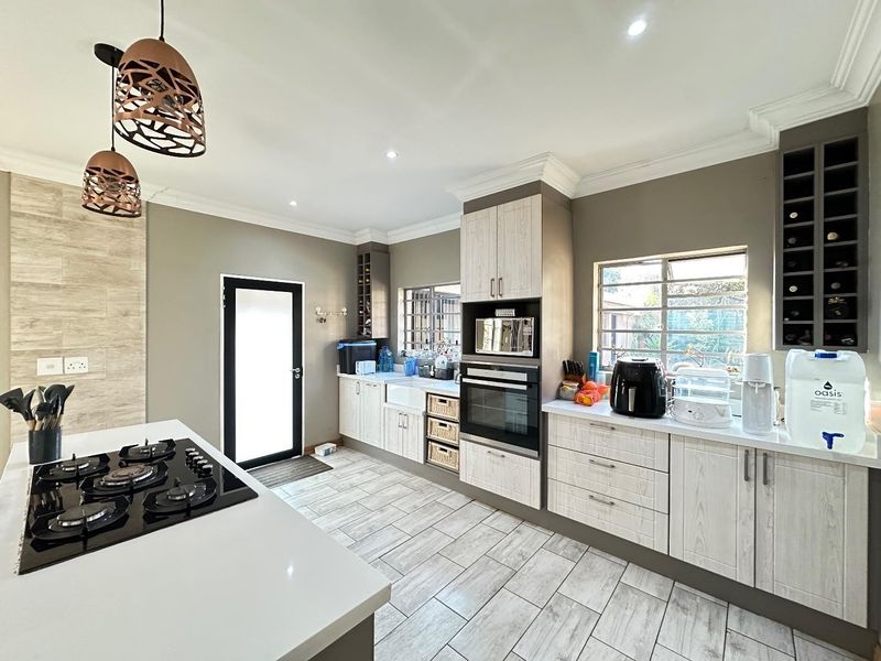 Modern kitchen featuring a gas hob on a central island, built-in oven and microwave, apron sink, and ample cabinetry with integrated wine storage.