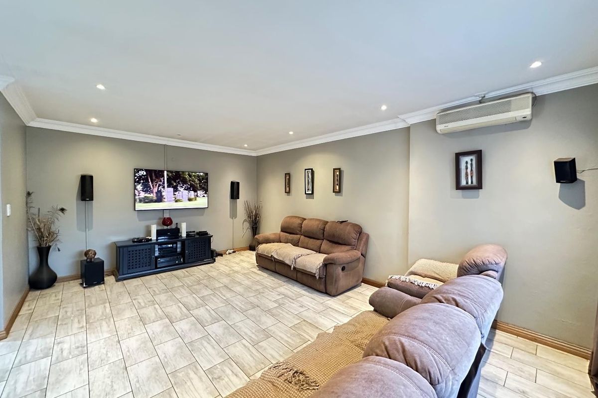 Spacious living room featuring tiled flooring, recessed downlighting, crown molding, and a wall-mounted split-system air conditioning unit.
