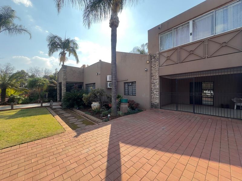 Front exterior view of the house featuring a paved driveway, stone cladding accents, security gates, and a balcony with security bars.