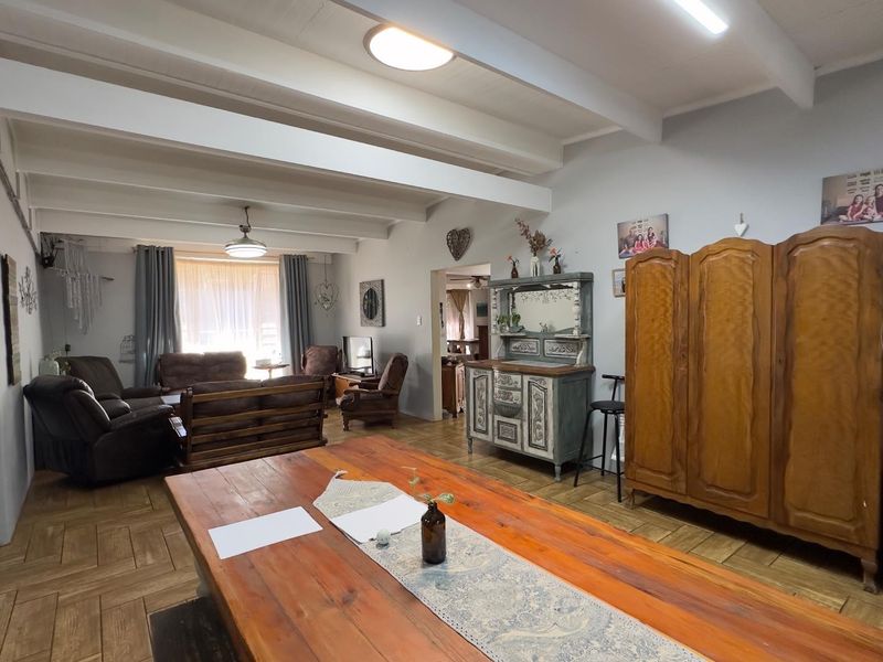 Spacious open-plan living and dining area featuring exposed ceiling beams and classic parquet flooring, offering a versatile layout for family living.