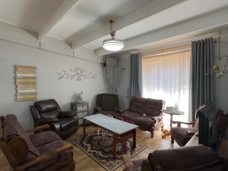 A cozy living room featuring exposed ceiling beams, tiled flooring, and a large sliding glass door that allows for natural light.