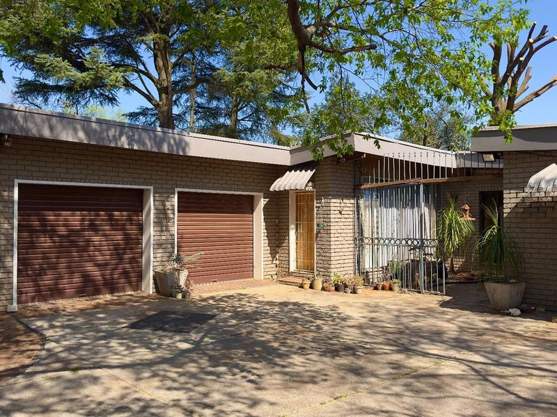 Front exterior view of a brick house featuring a double garage with roller shutter doors and a concrete driveway.