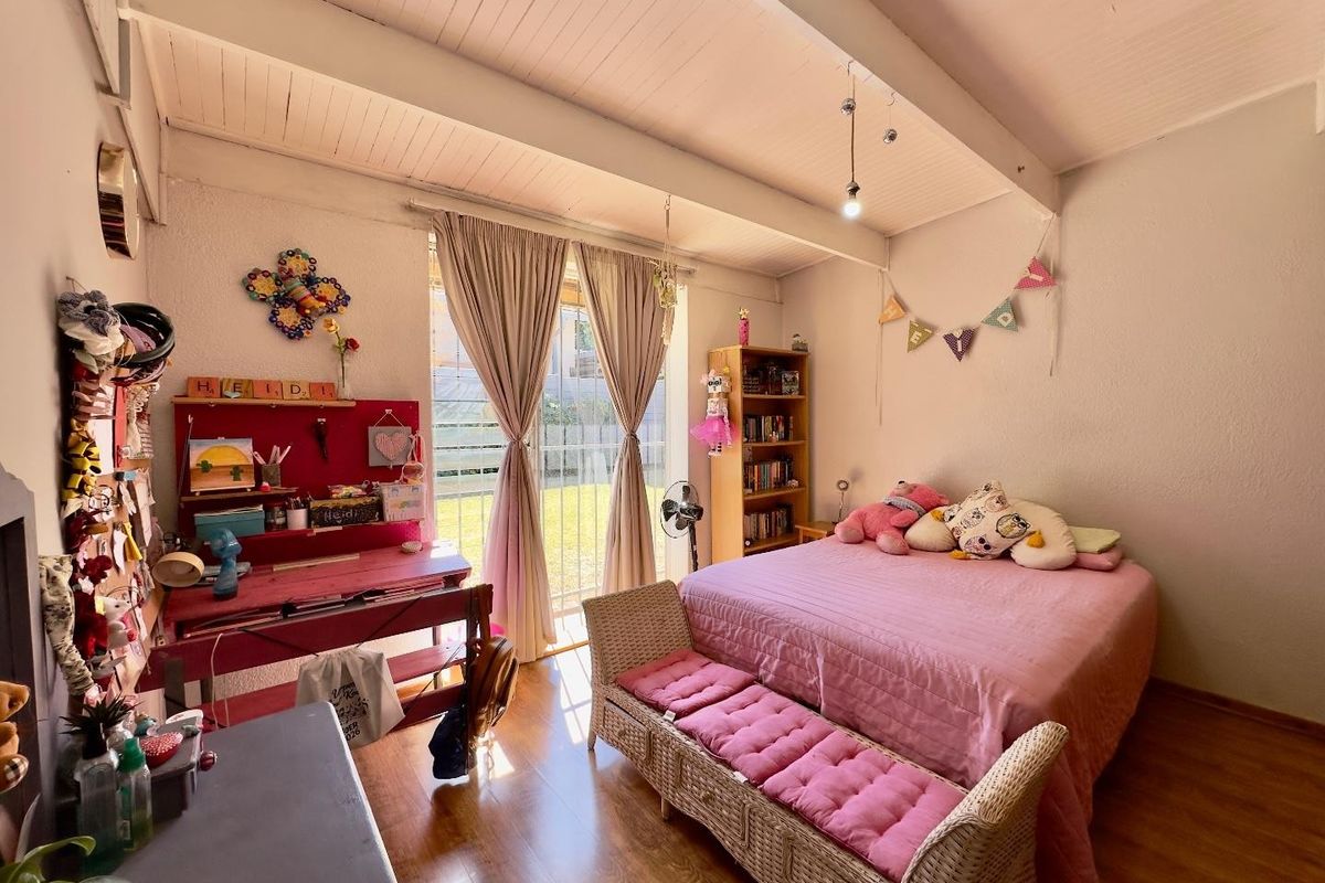 A bedroom featuring laminate flooring, exposed beam ceilings, and a sliding glass door providing access to the garden area.