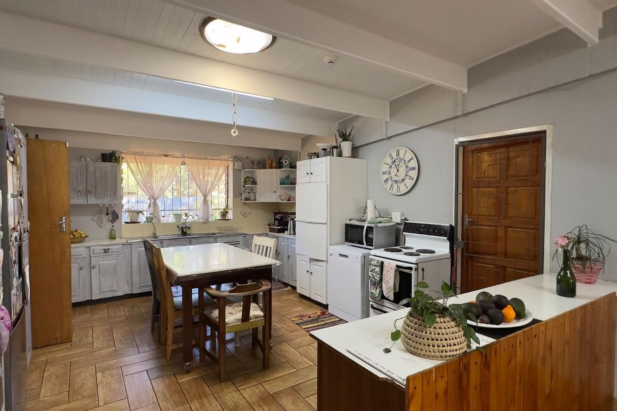 A functional kitchen featuring tiled flooring, exposed beam ceilings, built-in cabinetry, and a freestanding stove, offering a practical layout for daily meal preparation.