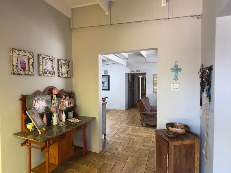 A bright hallway featuring herringbone tile flooring and exposed ceiling beams, providing a clear transition between living spaces.