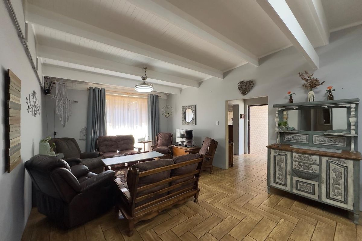 Spacious living room featuring exposed white timber ceiling beams and durable herringbone pattern floor tiles, offering a bright and comfortable living space.