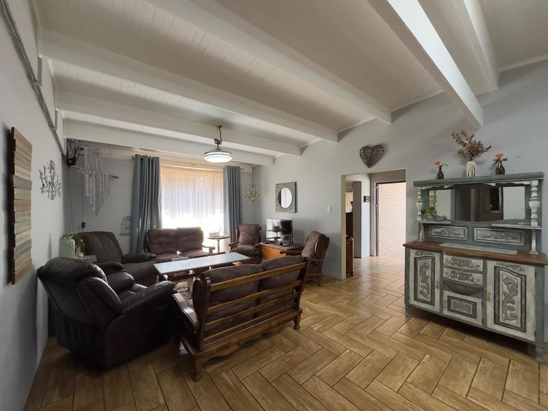 Spacious living room featuring exposed white timber ceiling beams and durable herringbone pattern floor tiles, offering a bright and comfortable living space.