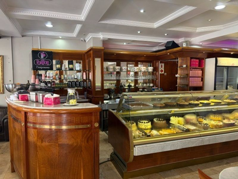 A well-maintained retail service area featuring a classic wooden counter, glass display cabinets for food items, and decorative ceiling finishes.