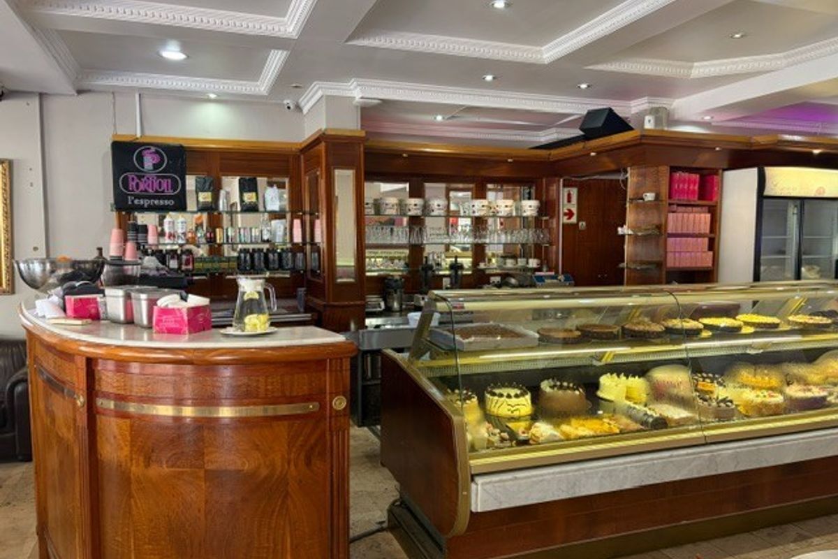 A well-maintained retail service area featuring a classic wooden counter, glass display cabinets for food items, and decorative ceiling finishes.