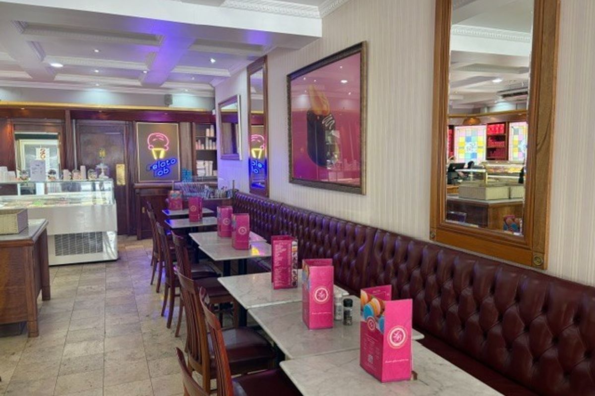 A well-maintained retail space featuring built-in leather banquette seating, decorative ceiling molding, recessed lighting, and tiled flooring, suitable for a cafe or restaurant.