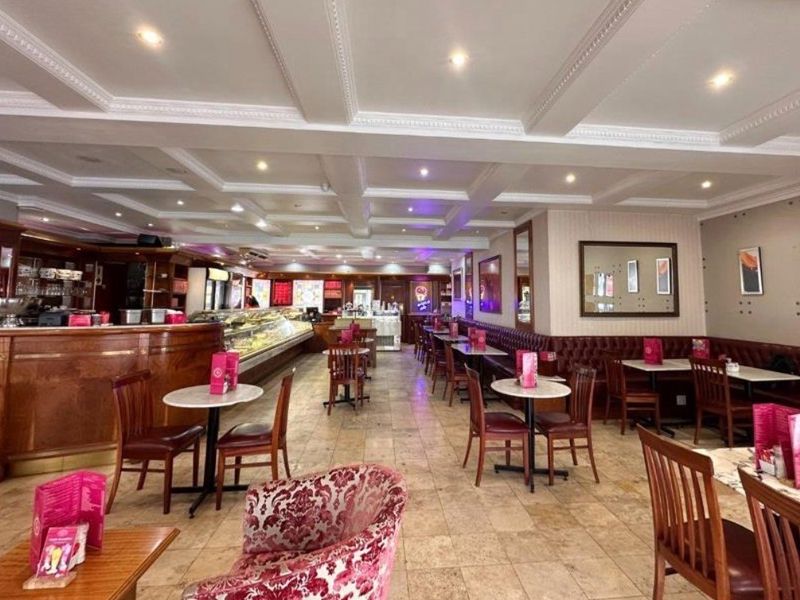 Spacious retail dining area featuring a coffered ceiling, recessed lighting, tiled flooring, and built-in service counter with integrated banquette seating.