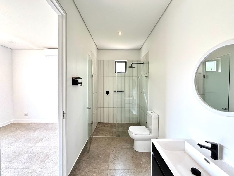 Modern bathroom featuring a walk-in shower with glass screen, contemporary black tapware, and a sleek vanity basin in a clean, neutral setting.