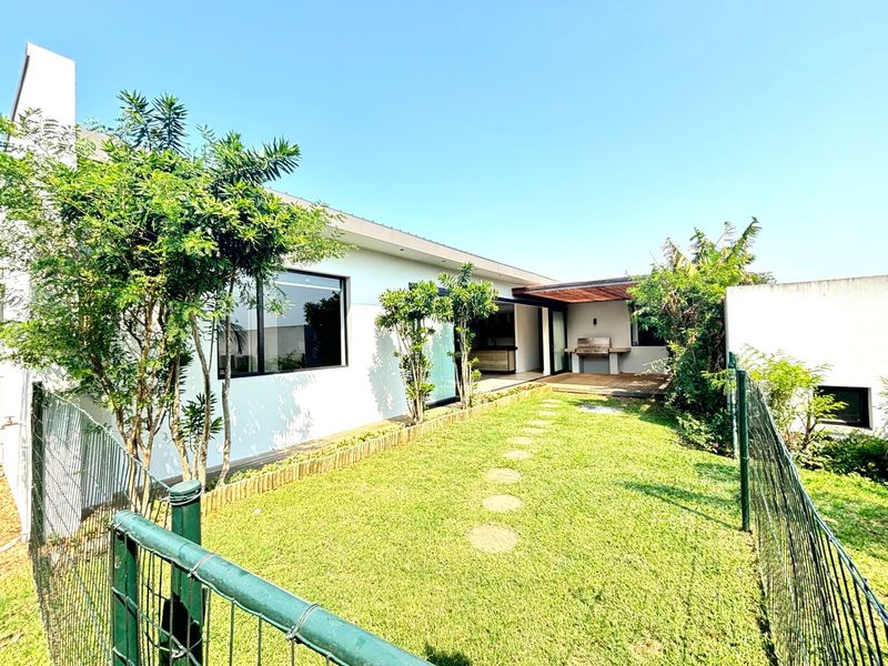 A well-maintained rear garden featuring a wooden deck, built-in braai area, and direct access to the interior through sliding doors.