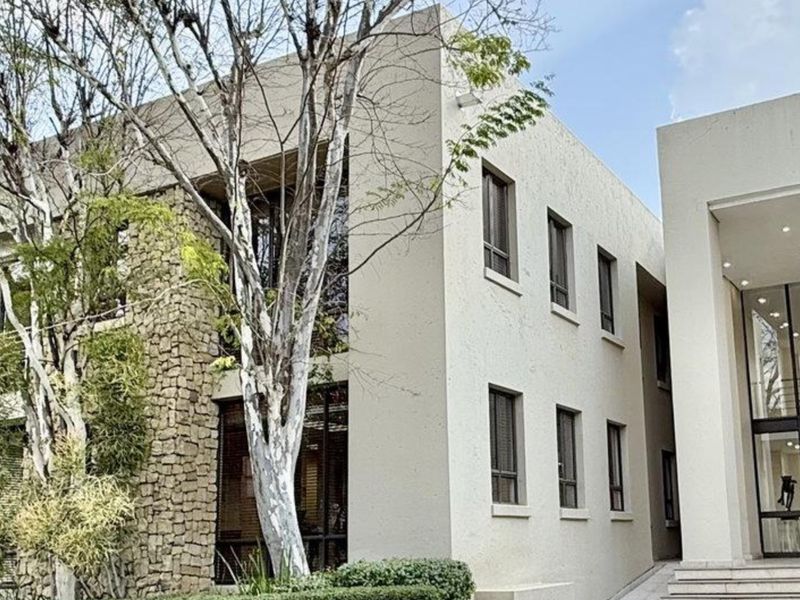 Modern commercial building facade featuring a combination of stone cladding, smooth stucco finish, and expansive glass windows with a prominent entrance.