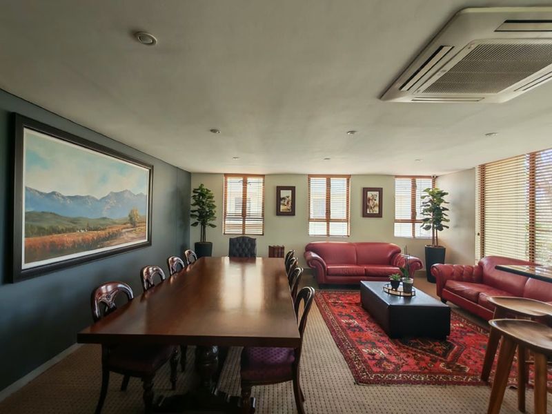 A spacious open-plan commercial meeting and lounge area featuring recessed lighting, ducted air conditioning, and large windows with venetian blinds.