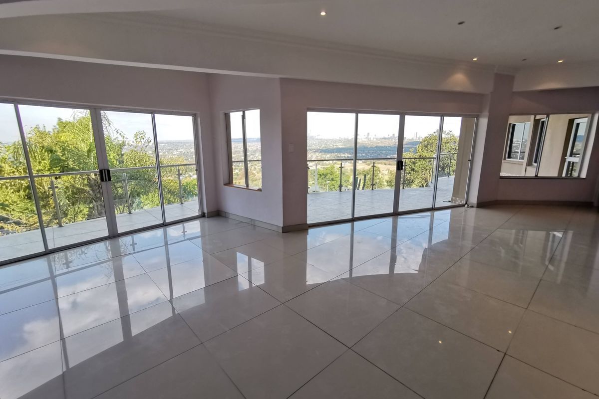 Spacious, light-filled living area featuring large format porcelain tiles, recessed lighting, and expansive sliding glass doors opening to a balcony with panoramic views.