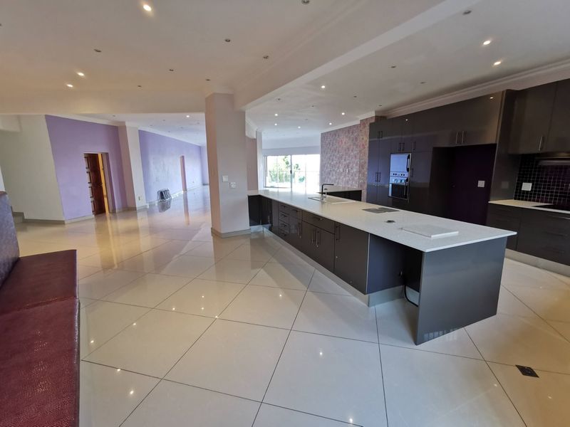 Spacious open-plan living area featuring a modern kitchen with a large island, built-in appliances, and polished tile flooring throughout.