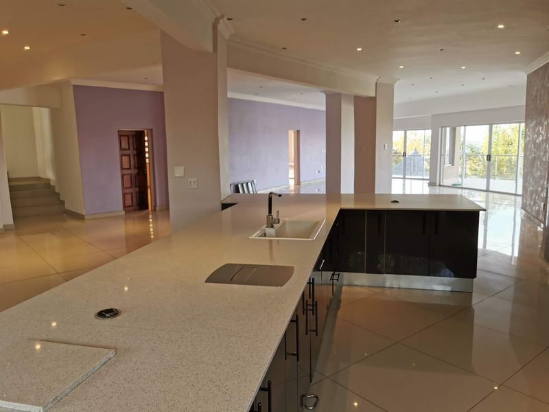 Spacious open-plan living area featuring a modern kitchen island with stone countertops, tiled flooring, and large sliding doors leading to an outdoor space.