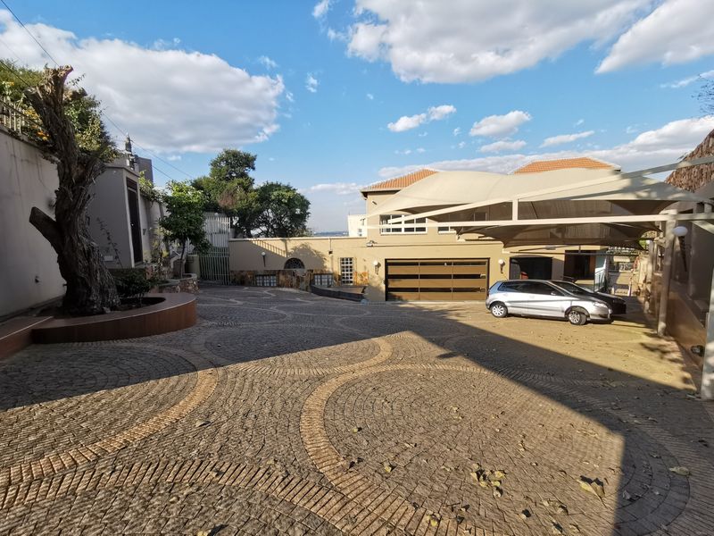 Spacious paved driveway leading to a garage with a large shade sail structure, providing ample parking space in a well-maintained exterior setting.