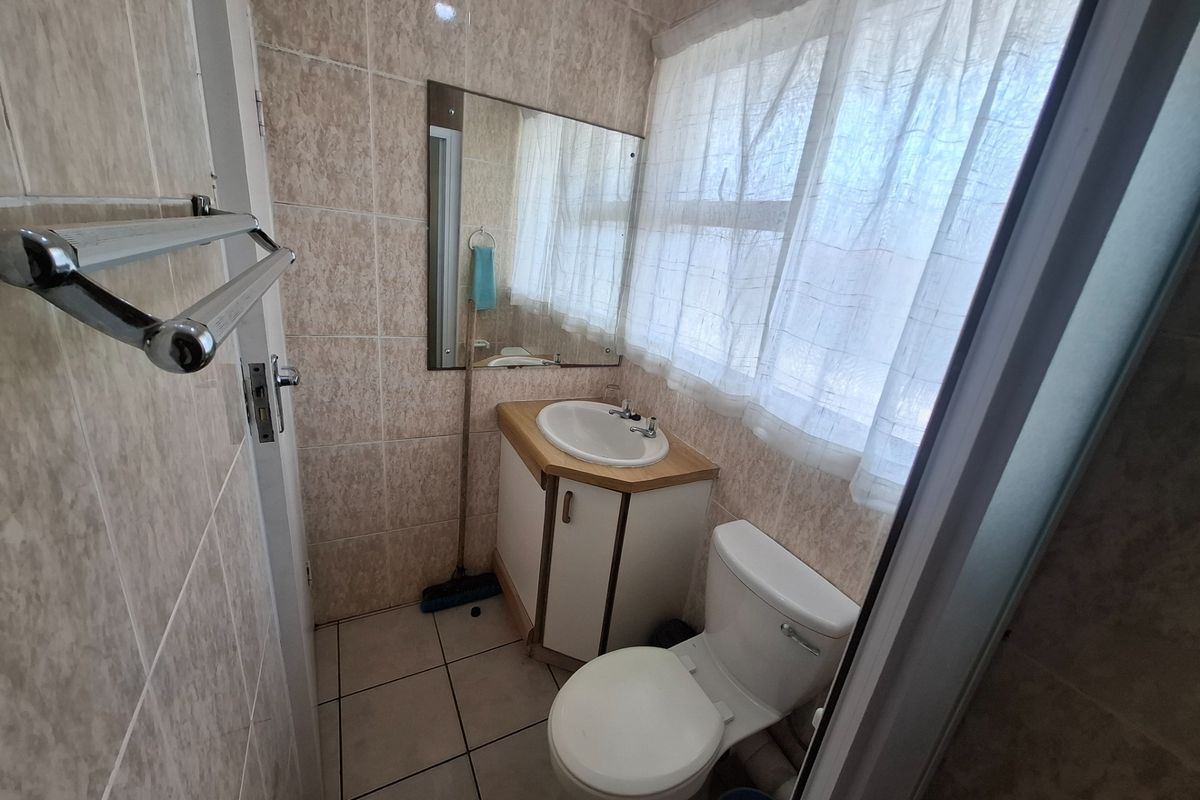 A functional bathroom featuring tiled walls and floors, a vanity cabinet with a basin, and a standard toilet.