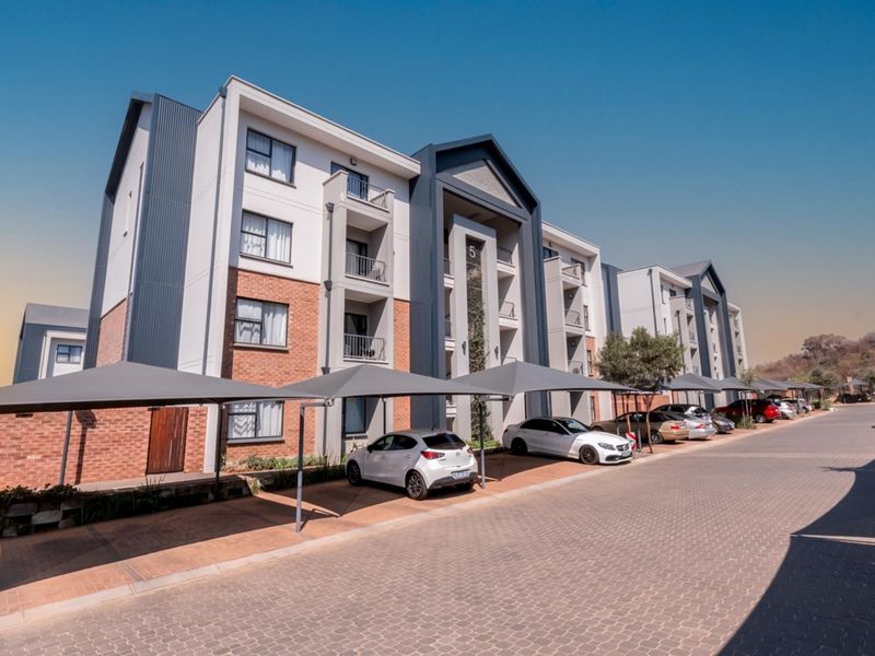 Modern apartment complex exterior featuring brick and panel facade, private balconies, and dedicated covered parking bays.