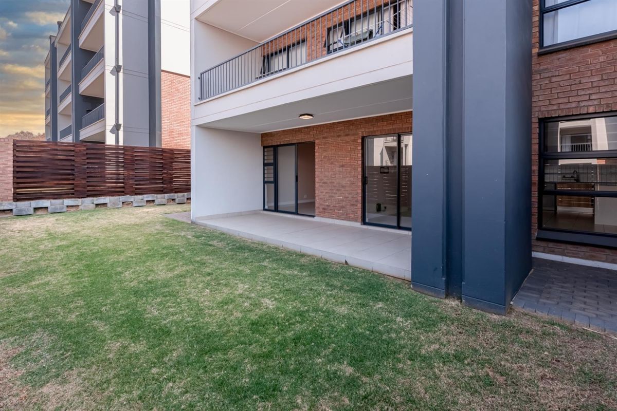 Ground floor apartment featuring a private tiled patio, sliding door access, and a small garden area with timber fencing.