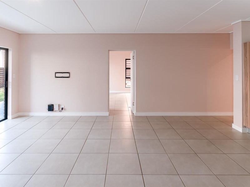 A bright, open-plan living area featuring neutral tiled flooring, built-in cabinetry, and a sliding glass door providing access to the outdoor space.