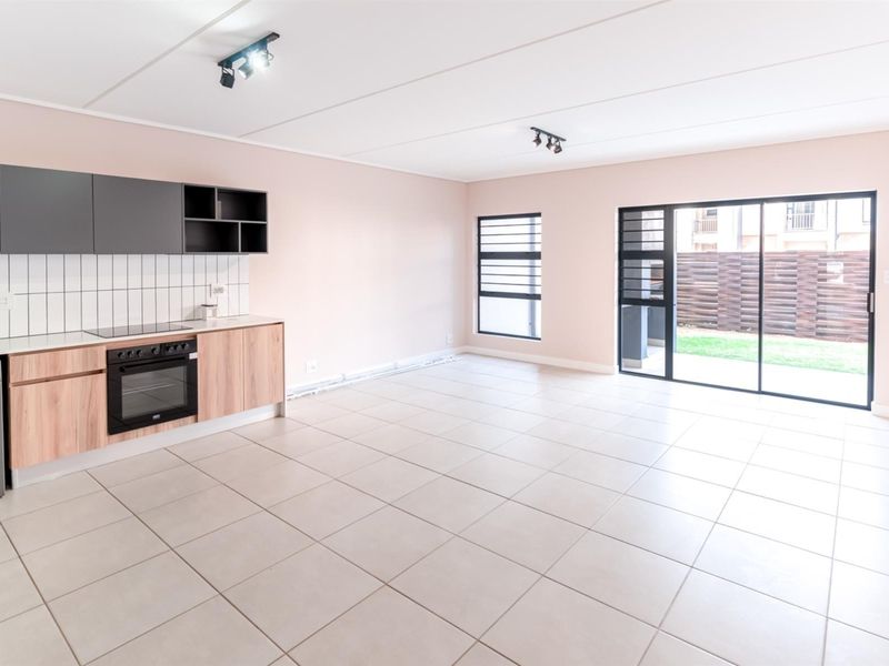 Spacious open-plan living area featuring a modern kitchen with built-in cabinetry, electric oven, hob, and direct access to the outdoor space via sliding doors.