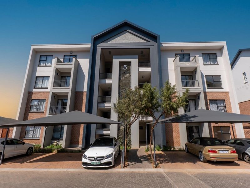 Modern multi-story apartment building facade featuring brick and render finishes, private balconies, and dedicated shade cloth parking bays.