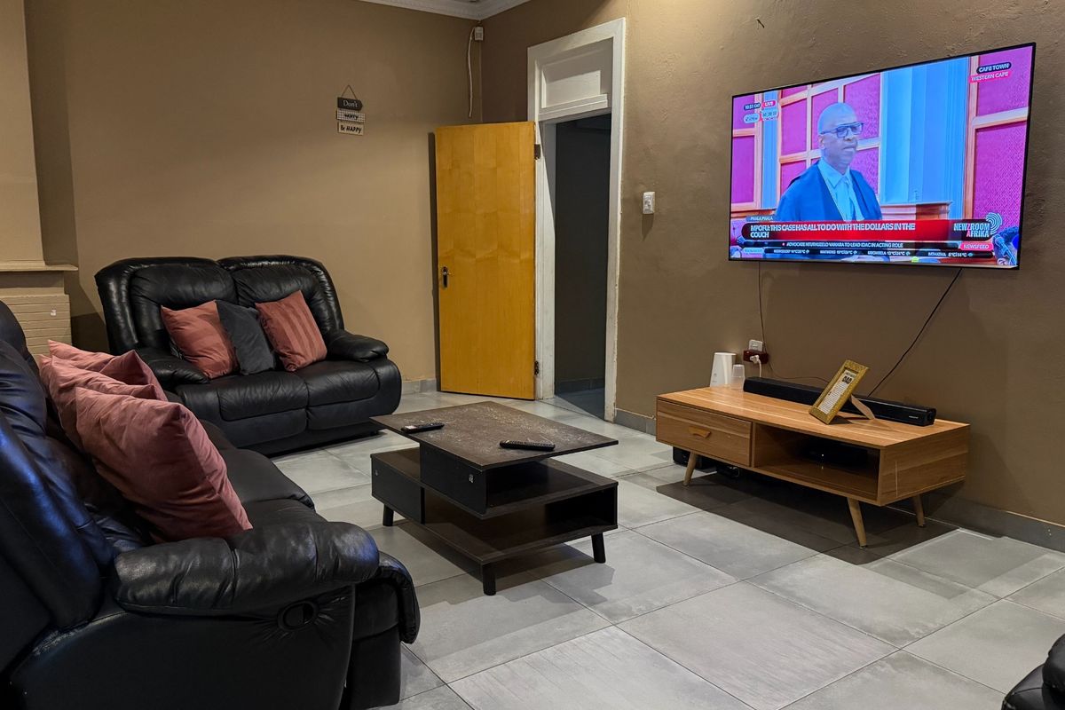 A comfortable living room featuring tiled flooring, coved ceiling details, and a wall-mounted television setup.