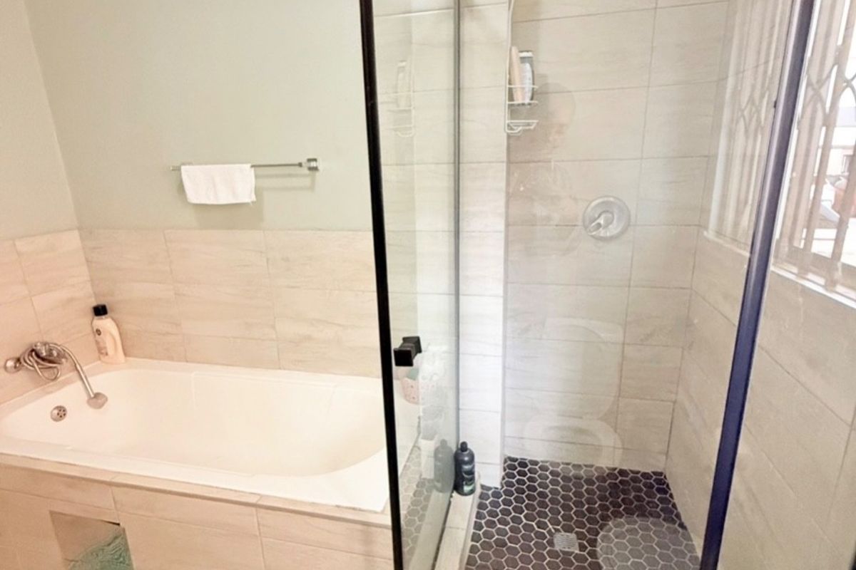 Modern bathroom featuring a built-in bathtub and a separate glass-enclosed shower with contemporary hexagonal floor tiling and a rain shower head.