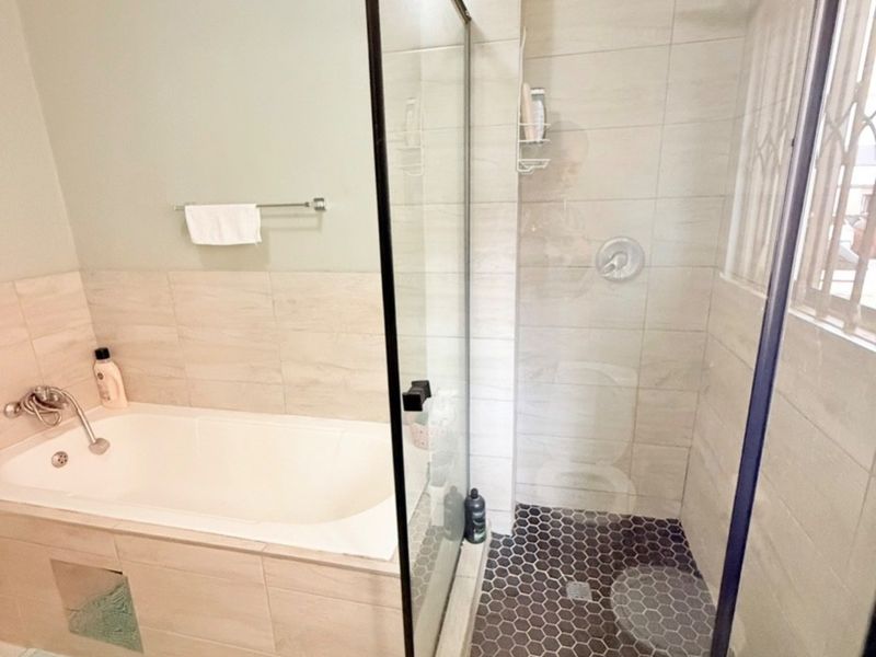 Modern bathroom featuring a built-in bathtub and a separate glass-enclosed shower with contemporary hexagonal floor tiling and a rain shower head.